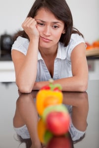 Woman looking at some fruits bored of healthy eating